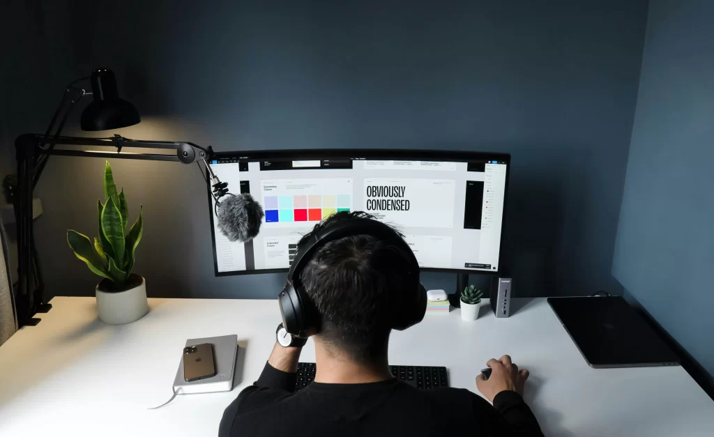 : Man sits at computer working on the visual aspects of a brand. 