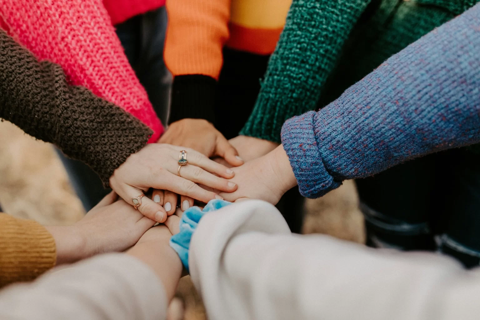 A diverse community of people holding hands together.