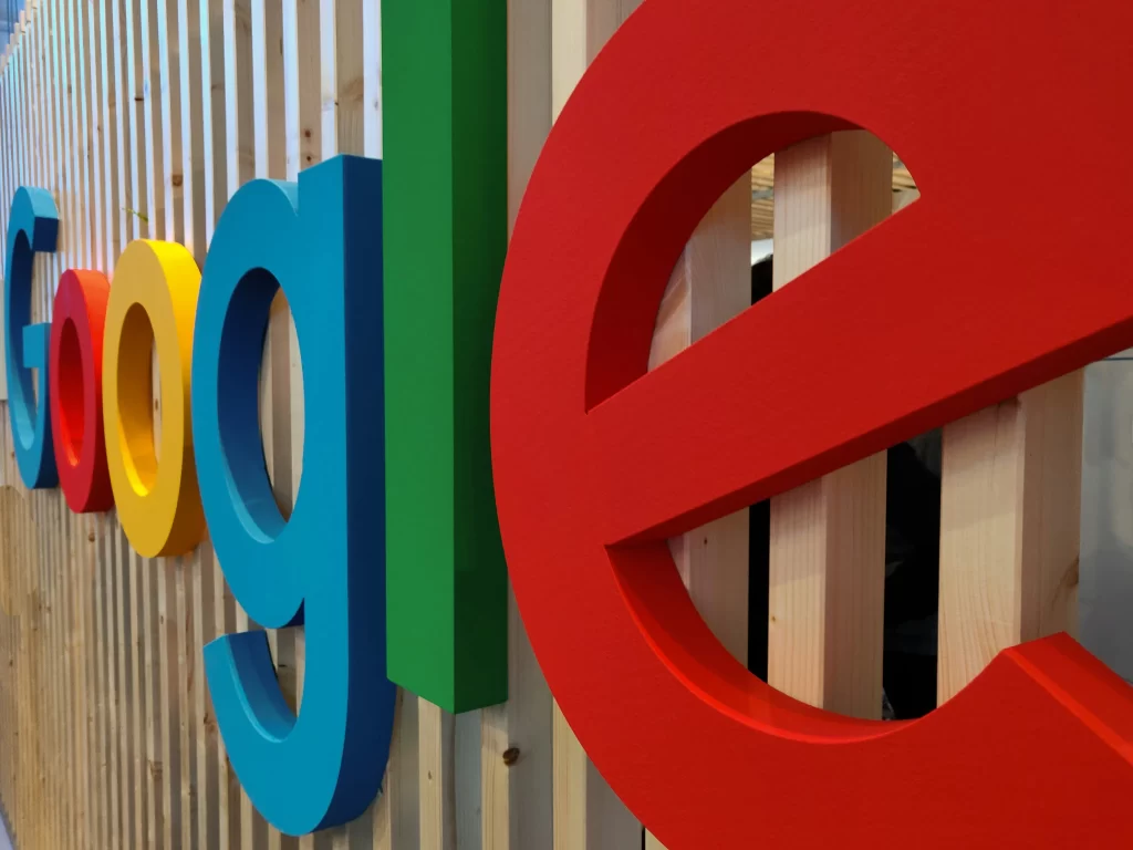 A side view of Google’s colorful logo on a wooden panel backdrop. 
