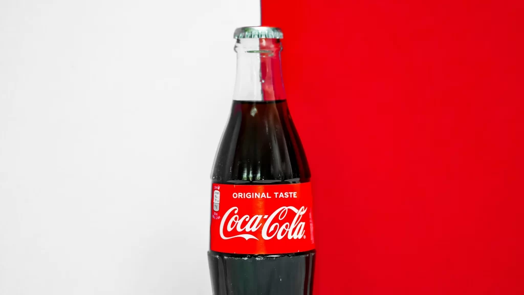 A bottle of Coca-Cola on a red and white background. 