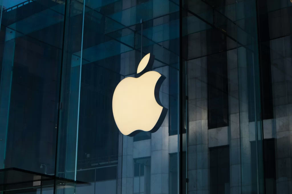 The sleek white Apple logo on a glass pane of a building. 