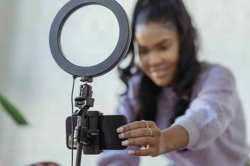 A woman influencer taking a selfie with a phone and ring light.