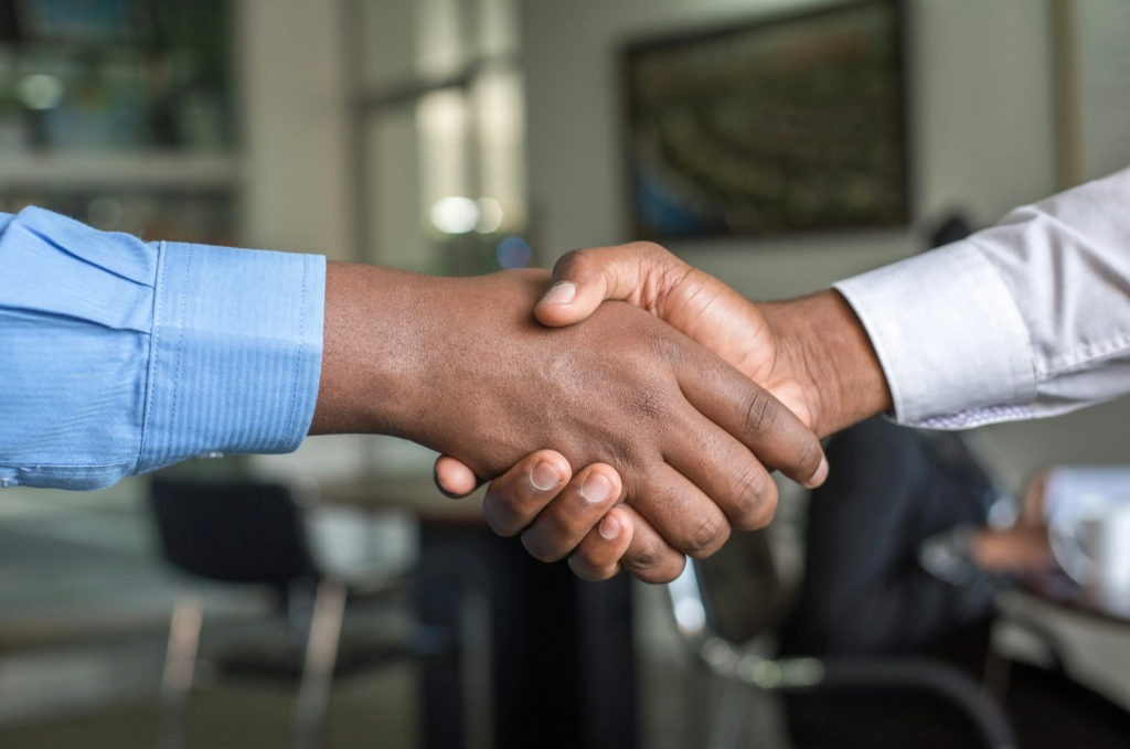 Two professionals shaking hands in a modern office setting, showing a successful business deal.