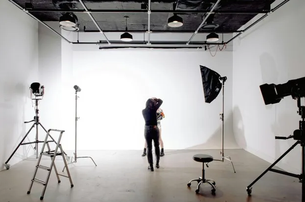 Photo studio with lots of lighting and two people take pictures.