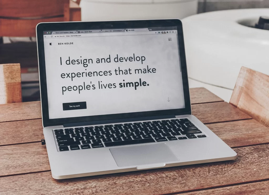 A laptop screen with a tab open that says “I design and develop experiences that make people’s lives simple.” 