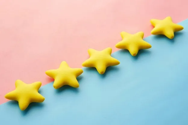 5 3D gold stars laying on a blue and pink background.