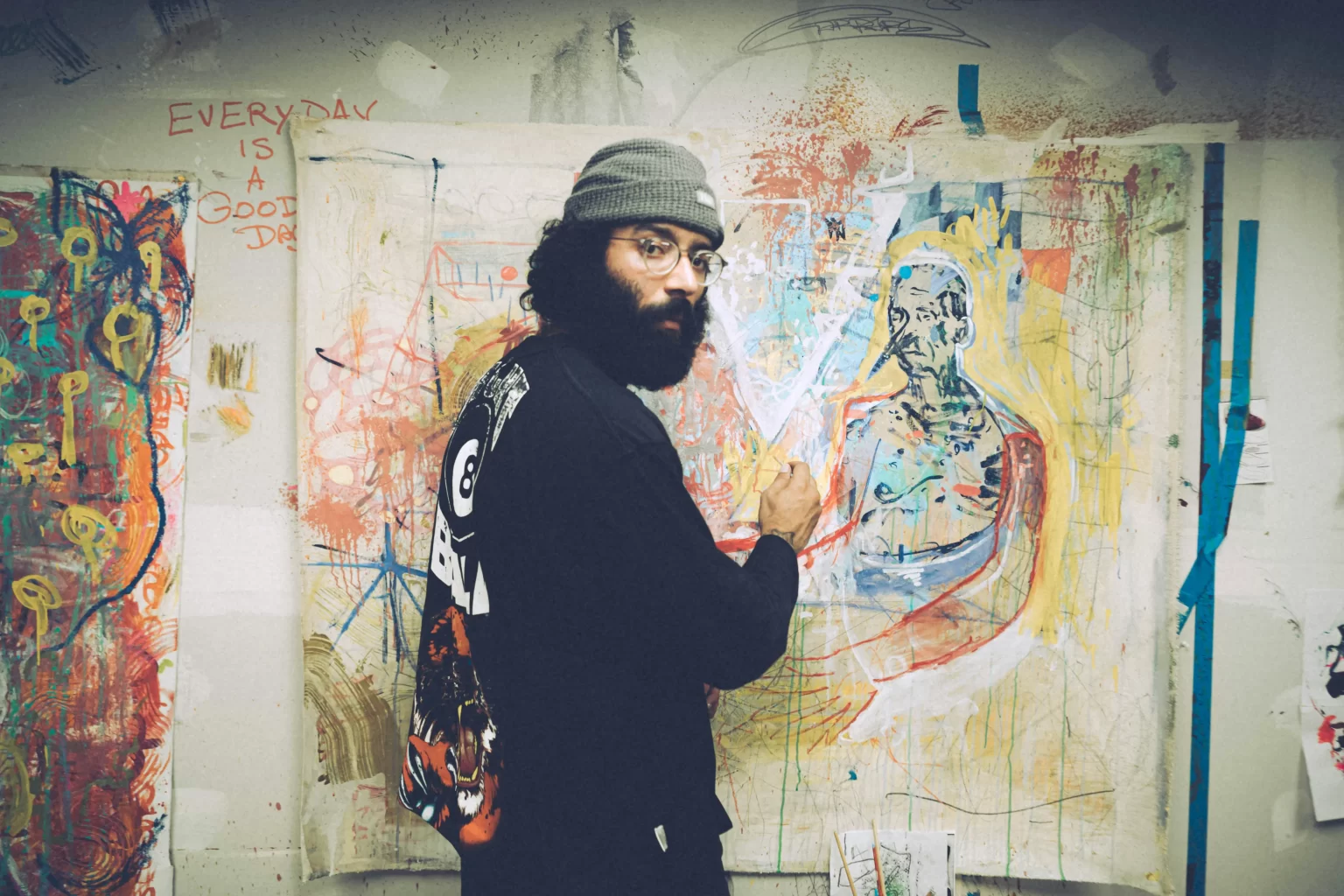 Man in hat standing in front of his artistic creations.  