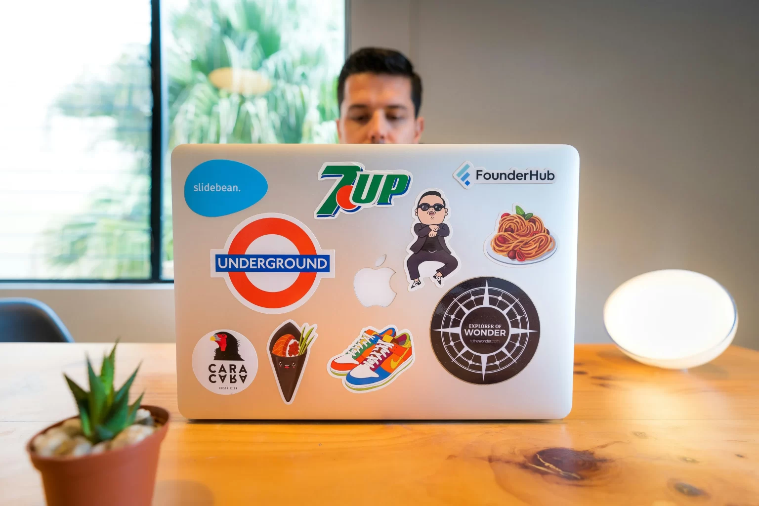 man sitting in front of laptop with multiple stickers on the cover. Showing his personality. 