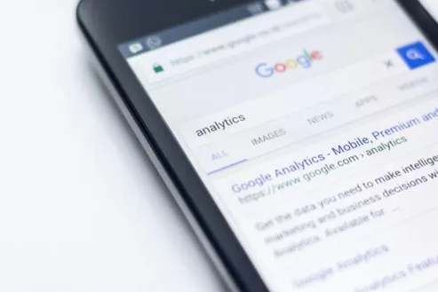 a phone laying on a table with a Google search for analytics on the screen. 