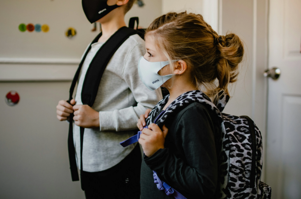 Two young girls with backpacks and face masks.  