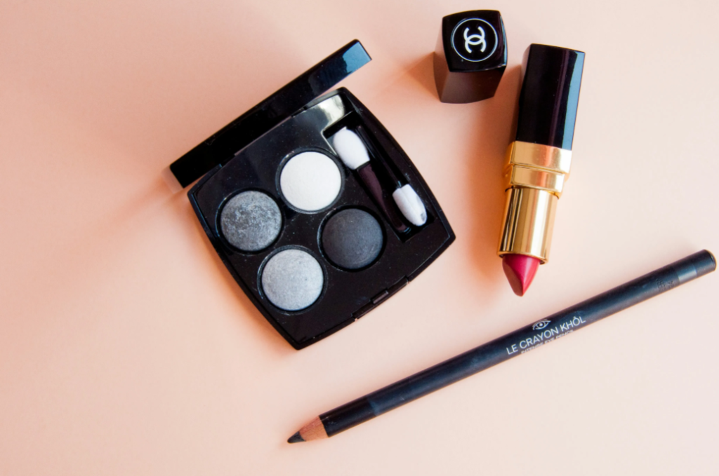 A Chanel eyeshadow palette, lipstick, and eyeliner on a table. 