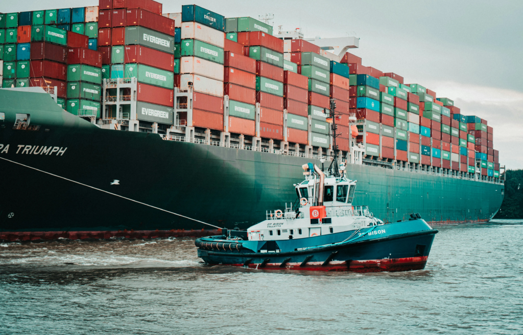 : A large cargo ship in the background with a smaller ship in the foreground