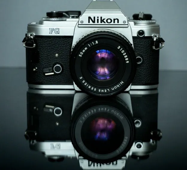 A vintage Nikon FG camera with a mirrored reflection.