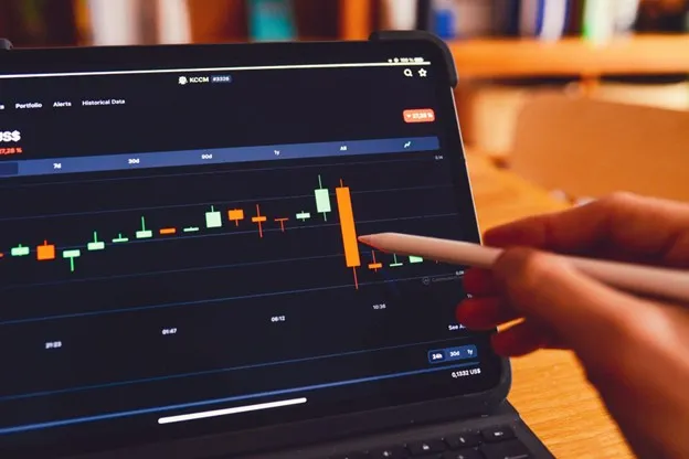 A person uses a stylus to analyze a stock market chart displayed on a tablet.