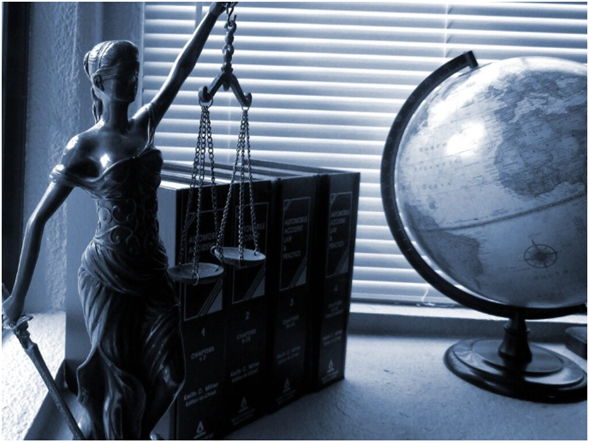 A statue of Lady Justice holding scales, next to law books and a globe, symbolizing justice, law, and global legal practice.