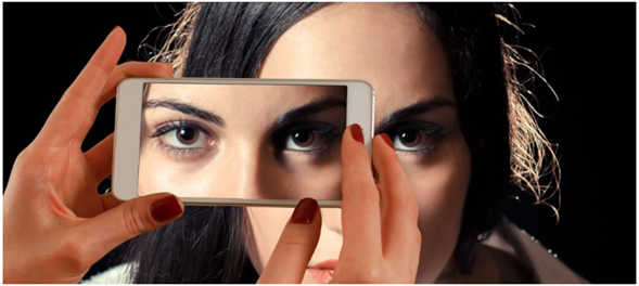 A person holding a phone displaying a close-up of their eyes, aligned with their real face.