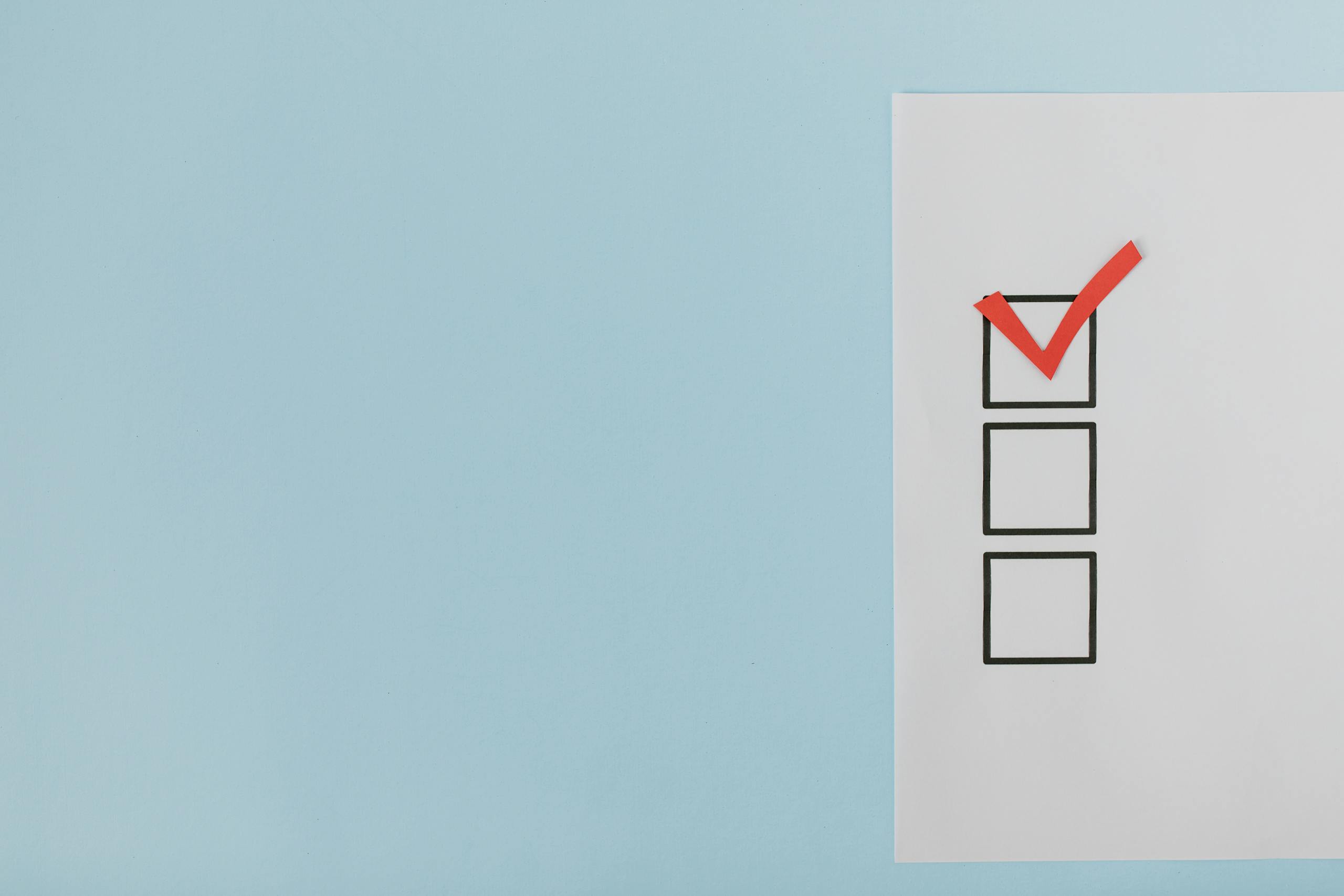 A minimalist checklist with a red checkmark on a blue background, providing ample copy space.